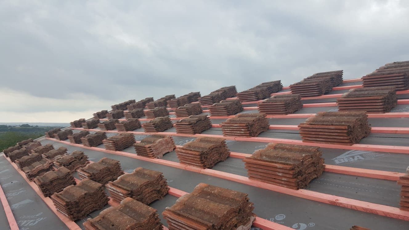 New roof tiles loaded out on fresh battens, with a view over the valley